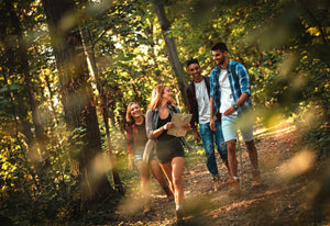 Group of four friends having fun hiking through a forest and checking their map.